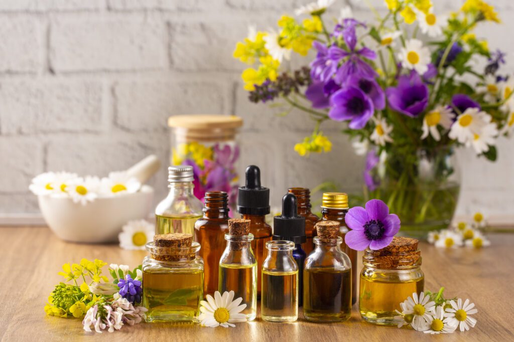 Essential oils with flowers on wooden table.