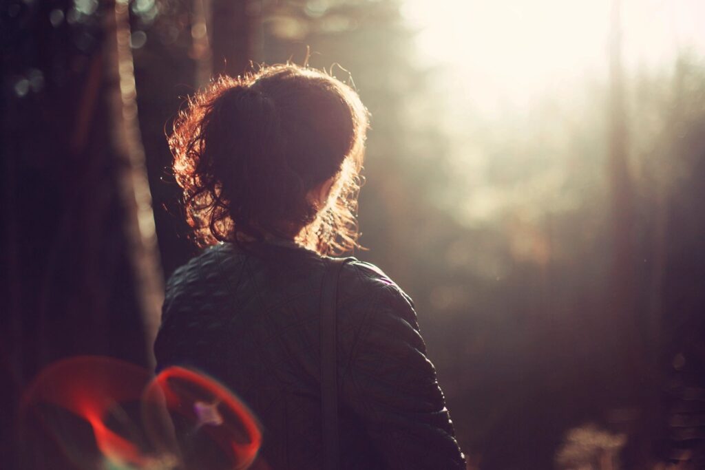 Person standing in sunlit forest clearing.
