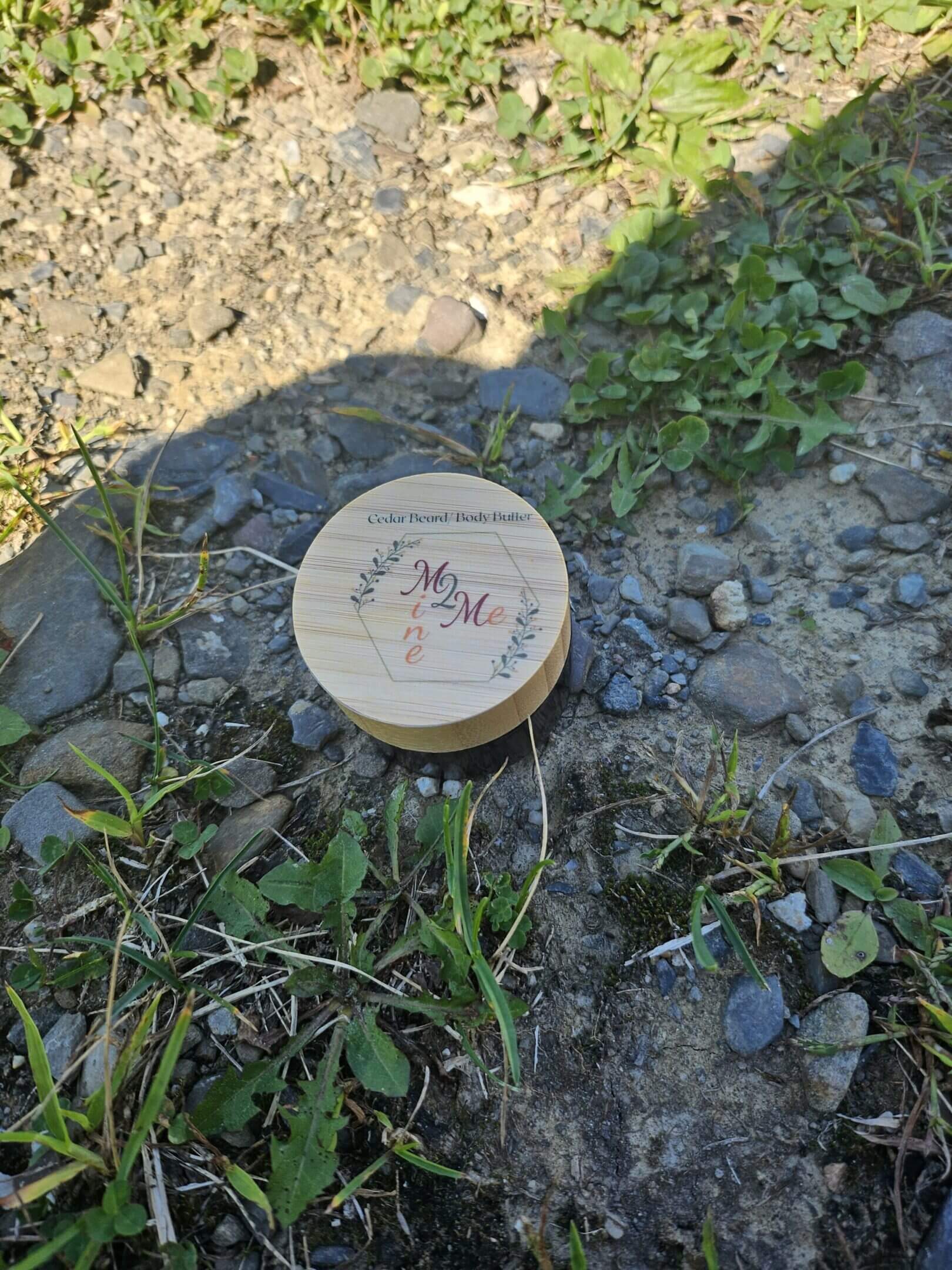 Wooden lid on rocky ground with grass.