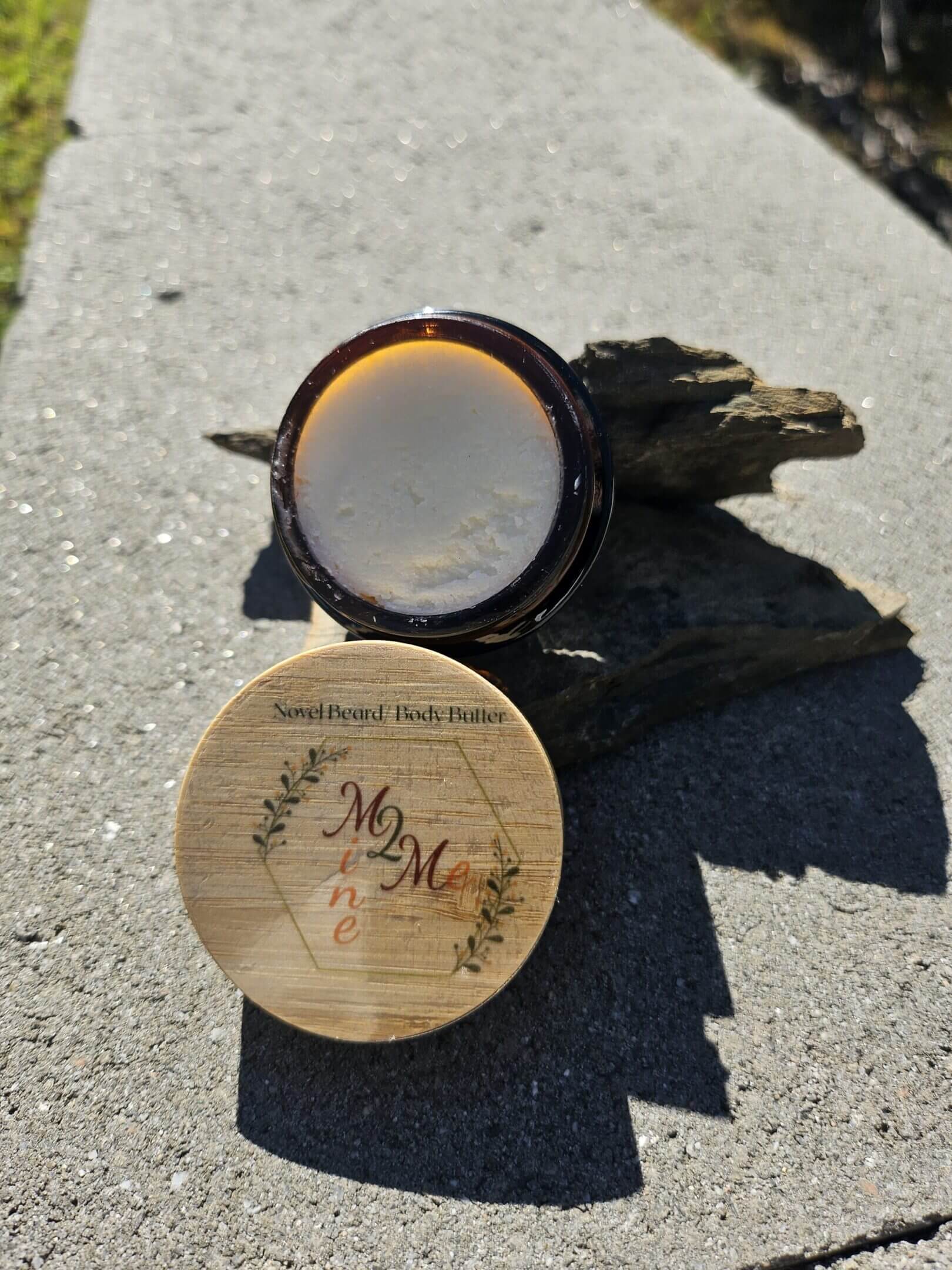 Beard balm container on stone surface.