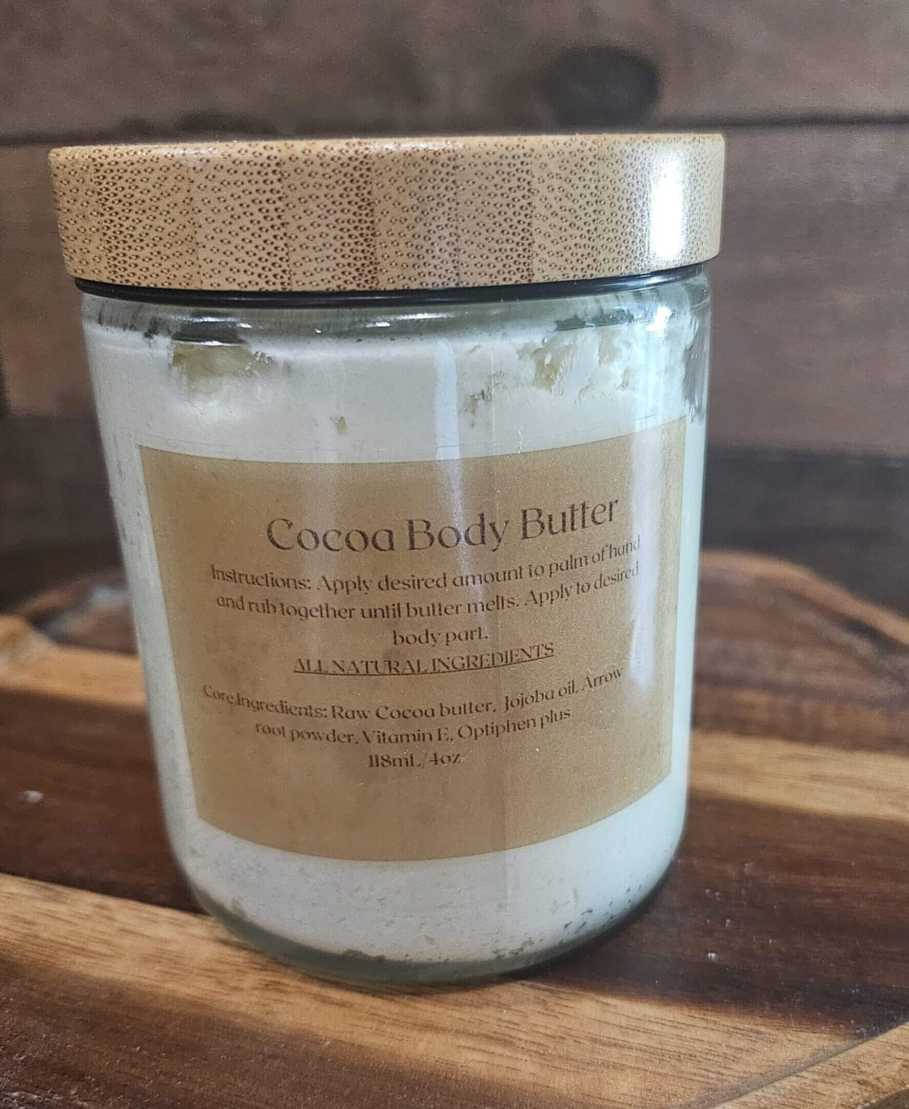Cocoa body butter jar on wooden surface.