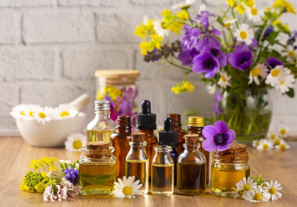 Essential oils with flowers on wooden table.